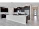 Bright kitchen with large center island, stainless steel refrigerator, and sleek dark cabinetry at 11357 Satire St, Orlando, FL 32832