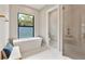 Bright bathroom featuring a soaking tub, large window, and glass-enclosed shower at 1904 Illinois St, Orlando, FL 32803