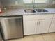 A stainless-steel dishwasher sits beneath a sink and granite countertops, with white cabinets at 16 N Lancelot Ave, Orlando, FL 32835