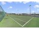 Community tennis court featuring a green surface with a net and lights at 2686 Maxwell W Ct, Kissimmee, FL 34743