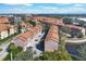 A picturesque aerial view of a condo community by a pond, showcasing lush landscaping and Spanish tile roofs at 6107 Metrowest Blvd # 104, Orlando, FL 32835