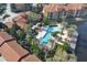 Aerial view features community pool with palm trees, clubhouse, lush landscaping, red tile roofs, and a serene pond at 6107 Metrowest Blvd # 104, Orlando, FL 32835