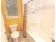 Bright bathroom showcasing a bathtub with shower, white tile, and a toilet near a window at 1511 Alligator St, St Cloud, FL 34771