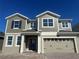 New two-story home showing attractive siding, a brick driveway, and a two-car garage with carriage door hardware at 5304 Teirgarten St, Saint Cloud, FL 34771