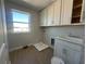 Well-lit laundry room featuring a single window, tile floors, and ample storage space with white shaker cabinets at 5304 Teirgarten St, Saint Cloud, FL 34771