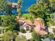 Aerial view of a beautiful custom home with a red tile roof, lush landscaping, and a private dock at 4024 W Danby Ct, Winter Springs, FL 32708