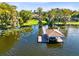 An aerial view showing a large property with lake access, a dock with a boathouse, and mature trees at 4024 W Danby Ct, Winter Springs, FL 32708