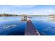 Long dock leading to a covered boat dock on a serene lake setting with lily pads and distant shores at 4024 W Danby Ct, Winter Springs, FL 32708
