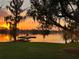 Scenic lakeside view with a charming covered boat dock, Spanish moss, and vibrant sunset reflecting on the calm water at 4024 W Danby Ct, Winter Springs, FL 32708