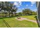 Spacious backyard with green grass, a black fence lining the water, and a quaint fire pit area at 1546 Water Elm Ct, Orlando, FL 32825