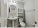 Cozy bathroom with a pedestal sink, round mirror, and a small storage cabinet above the toilet at 1546 Water Elm Ct, Orlando, FL 32825