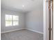 Neutral bedroom with carpet, base trim, a window overlooking the greenery, and a door leading out of frame at 8908 Sw 133Rd Ln, Ocala, FL 34473