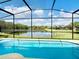 Inviting pool with screened enclosure boasts stunning views of a tranquil lake and lush landscaping at 2911 Sunset Vista Ct, Kissimmee, FL 34747