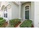 Green front door with arched window and neatly trimmed bushes at 8169 Fan Palm Way, Kissimmee, FL 34747