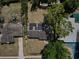 Birds-eye view of a home with solar panels on the roof, surrounded by mature trees and green lawns at 5018 Figwood Ln, Orlando, FL 32808