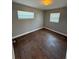Bedroom features wood-look floors, fresh paint, two windows, and modern lighting at 5018 Figwood Ln, Orlando, FL 32808