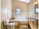 Well-lit bathroom featuring a soaking tub, tiled walls, and a neutral-toned vanity cabinet at 5240 N Lake Burkett Ln, Winter Park, FL 32792