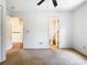 Bright bedroom with a ceiling fan and neutral carpet with access to the hallway and bathroom at 5240 N Lake Burkett Ln, Winter Park, FL 32792