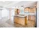 Bright kitchen features wood cabinets, stainless steel refrigerator, and island seating at 5240 N Lake Burkett Ln, Winter Park, FL 32792