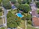 Aerial view of backyard pool with surrounding green yard, trees, and adjacent neighborhood streets at 5240 N Lake Burkett Ln, Winter Park, FL 32792