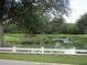 Picturesque pond featuring a waterfall, lush landscaping, and a classic white fence at 3621 Arlington Ridge Blvd, Leesburg, FL 34748
