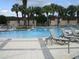 Community pool featuring multiple lounge areas and a pergola with mature palms and lush landscaping around the edge at 3621 Arlington Ridge Blvd, Leesburg, FL 34748