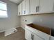 Functional laundry room with white cabinets, sleek black hardware, tile floors, and large bright window at 1366 Twelve Oaks Rd, Saint Cloud, FL 34771