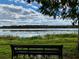 Scenic lake view featuring a bench, lily pads, and tree line with lush green grass at 3468 Soho St # 107, Orlando, FL 32835
