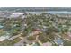 An aerial view captures a vibrant neighborhood with houses and lush trees near a lake and shopping centers at 1407 Edgewater Beach Dr, Lakeland, FL 33805