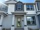 Two-story townhome with gray and white exterior, green door, and a paved driveway at 1344 Lumpini St, Saint Cloud, FL 34771