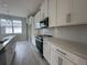 Open-concept kitchen with white cabinets, stainless steel appliances, quartz countertops, and tile backsplash at 1344 Lumpini St, Saint Cloud, FL 34771