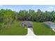 Aerial view of a modern home, featuring a wide driveway, green lawn and forest at 15123 Sw 61St Court Rd, Ocala, FL 34473