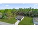 Aerial view of modern home, featuring a dark gray garage door, green lawn and large forest at 15123 Sw 61St Court Rd, Ocala, FL 34473