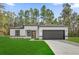 A modern home with white exterior, black trim, a dark gray garage door and a green lawn at 15123 Sw 61St Court Rd, Ocala, FL 34473