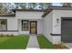 Modern home featuring a glass-paneled front door, white exterior, dark trim, and green lawn at 15123 Sw 61St Court Rd, Ocala, FL 34473