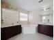 Bright bathroom featuring dual vanities, a soaking tub, and tile floors at 2142 Brandywine Falls Way, Orlando, FL 32824