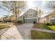Well-manicured front lawn with mature tree, two car garage, and two story home at 2142 Brandywine Falls Way, Orlando, FL 32824
