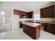 Well-appointed kitchen featuring dark wood cabinetry, a kitchen island, and tile flooring at 2142 Brandywine Falls Way, Orlando, FL 32824