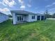 Rear view of the home showcasing a covered patio, sliding glass doors, and a well-maintained lawn at 2322 Lily Bloom Rd, St Cloud, FL 34771
