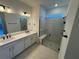 Sleek bathroom with double vanities, quartz countertop and a glass-enclosed shower at 2322 Lily Bloom Rd, St Cloud, FL 34771