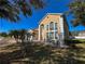 Two-story home with large arched windows, a three-car garage, lush landscaping, and a brick driveway at 2387 Laurel Blossom Cir, Ocoee, FL 34761