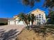 Front exterior featuring a tan stucco home with a three-car garage, brick driveway, and palm trees on a sunny day at 2387 Laurel Blossom Cir, Ocoee, FL 34761