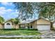 Tan house with a gray roof, lush lawn and mature trees at 1007 Tony Cir, St Cloud, FL 34772