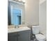 A bathroom featuring a gray vanity, white toilet, and a white tiled tub and shower at 5417 Fairwood Way # 304, Orlando, FL 32808