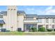 Beige two-story townhome featuring a blue roof, screened in porch, and manicured bushes at 5417 Fairwood Way # 304, Orlando, FL 32808
