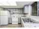 Well-lit kitchen featuring gray cabinets, white appliances, and granite countertops at 5417 Fairwood Way # 304, Orlando, FL 32808
