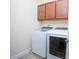 Bright laundry room featuring modern white washer and dryer with dark brown cabinets at 14046 Walcott Ave, Orlando, FL 32827