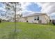 View of the backyard featuring a green lawn, fence, and the rear exterior of the house at 7889 Penrose Pl, Wildwood, FL 34785