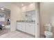 Bright bathroom features a large mirror, granite counters, and white cabinets at 7889 Penrose Pl, Wildwood, FL 34785