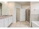 Bright bathroom showcasing double sinks with granite countertops, tiled floors, a shower, and a soaking tub at 7889 Penrose Pl, Wildwood, FL 34785